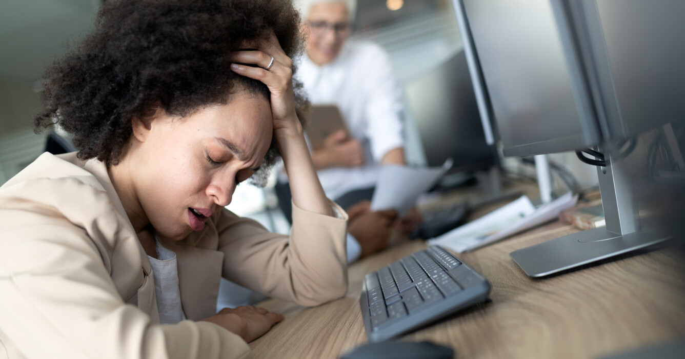 Une employée se tient la tête devant son ordinateur