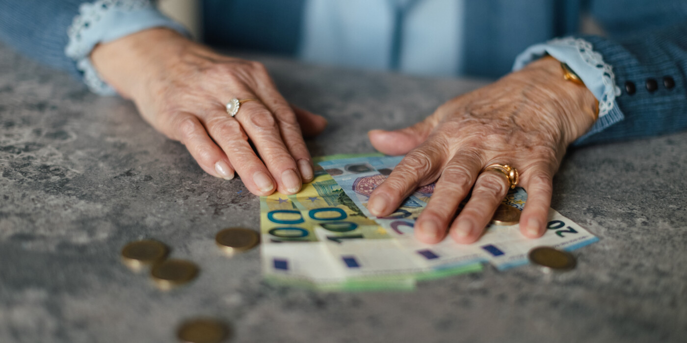 les mains d'une dame âgée posés sur des billets de banque